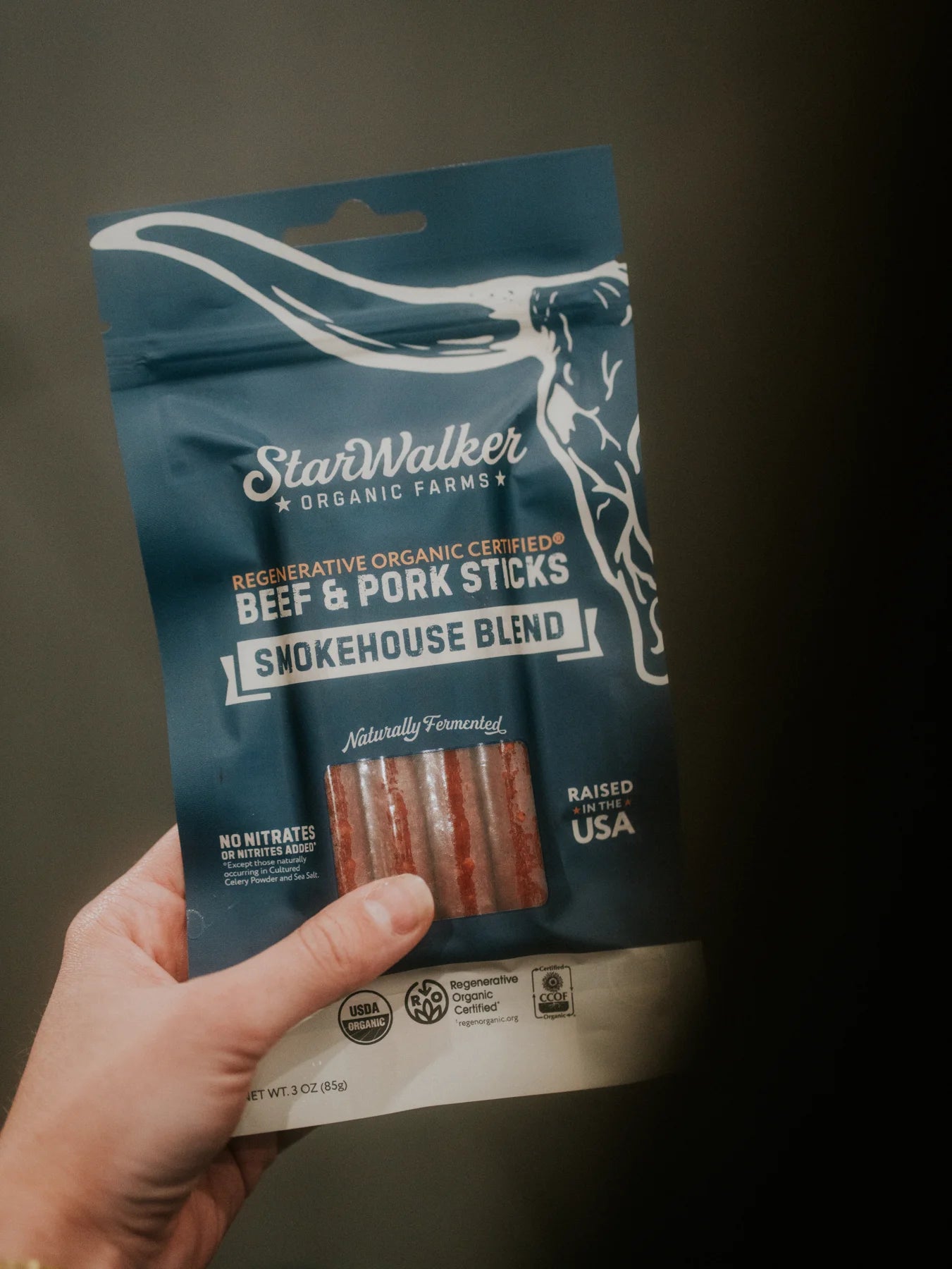 A hand holding StarWalker Smokehouse Blend meat sticks